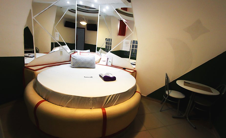 Cama redonda da Suíte Simples com iluminação ambiente